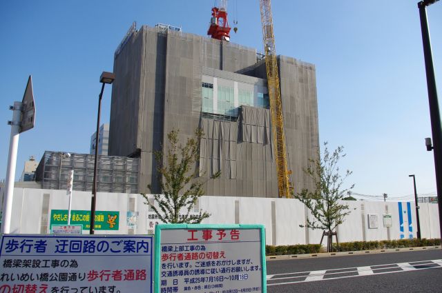 建設中の建物。工事音が響き工事車両が行き交う。