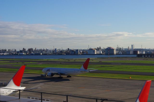 飛行機が誘導されていく。奥には煙突やタンクなど、川崎の工場地帯の建物が多数見える。普段なかなか見ることができない風景ですね。