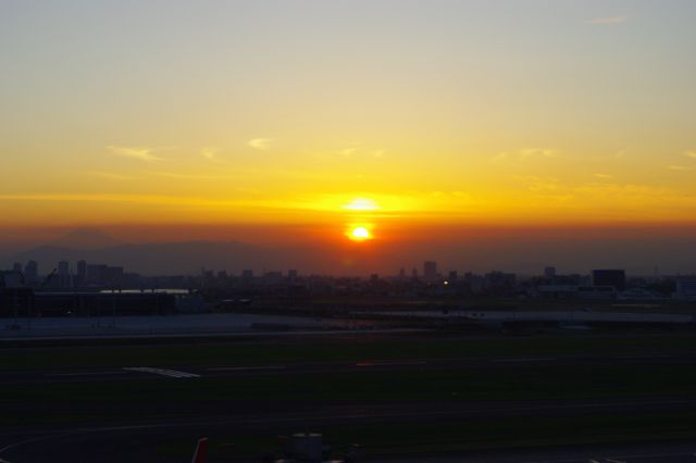 西側、夕陽が沈んでいく。夕陽の周りは一段と輝かしいオレンジ色でまぶしい。左側には富士山のシルエットが見える。