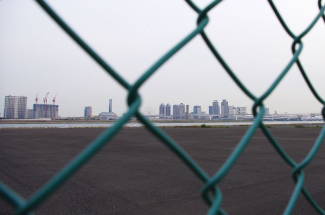 海岸沿いの広い空き地の奥にはお台場が見える。