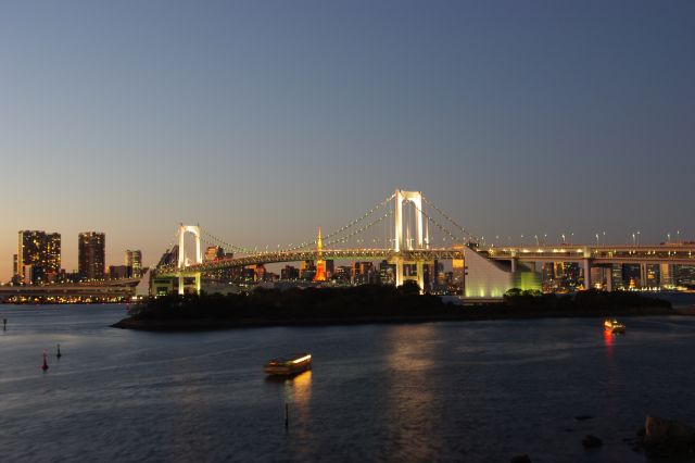 日没直後の一番美しい時刻に、台場駅付近より撮影しました。遠くの空が夕焼け色で、徐々に青い夜空へと染まっていき、都市の灯りが映えていく。屋形船もいくつか見られ、夜景の灯の１つとなっていました。