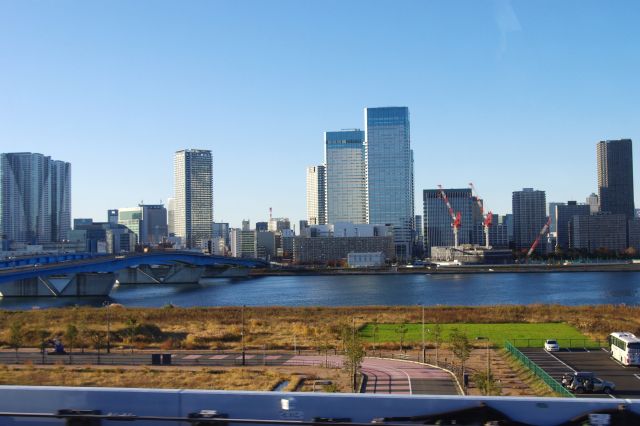 豊洲駅を出ると右側には晴海大橋と晴海のビル群の街並み。手前は空き地が広がる。