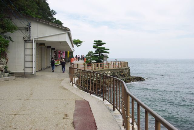 潮の香りが漂う海岸沿いの参道。岩山が迫る。