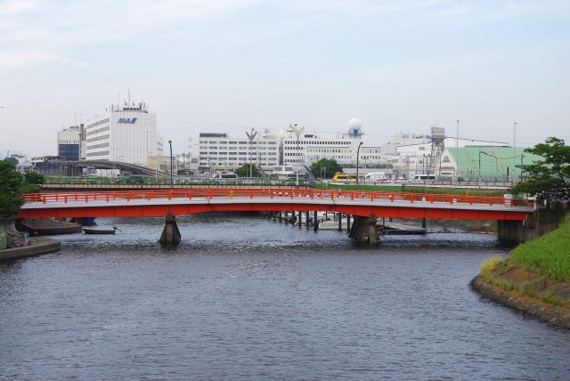 北側には朱色の欄干の稲荷橋。奥には空港関連施設。