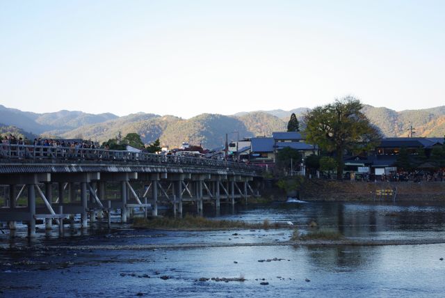 渡月橋背後には紅葉の山並み。