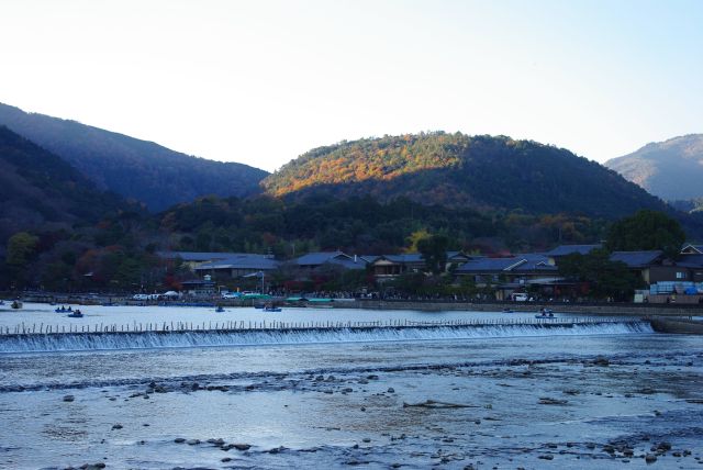 渡月橋背後には紅葉の山並み。