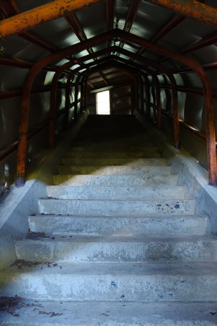 小窓から中を覗く。階段の通路が続く。遺構、廃墟、ダンジョン感。