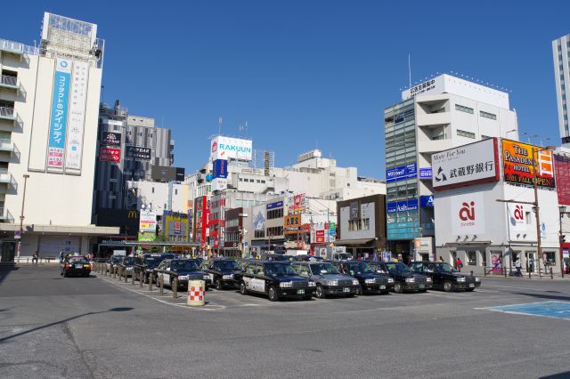 ロータリー中央にはタクシーが集まり周囲は西口より低層のビル群。