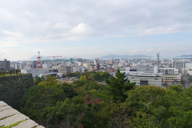 北西側、丸亀の町並みや島々。左側には二の丸の石垣が迫ります。