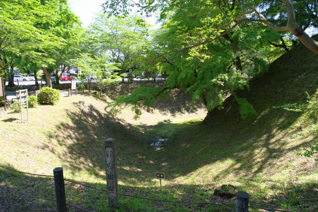 左手の空堀。奥には駐車場。