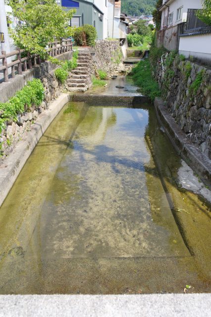 橋から紺屋川の上流方向、住宅の合間を流れています。