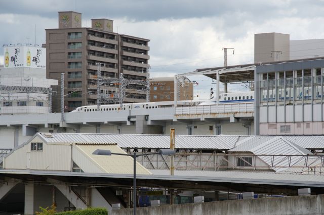 在来線ホームの先に行き来する新幹線が見えます。