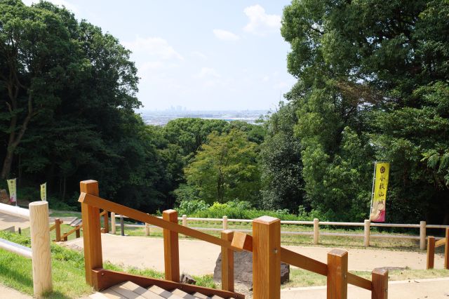 階段を登ると横切る道へ、振り返ると木々の切れ間に少し景色が。