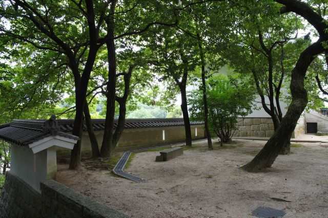 階段上、狭間のある低い塀の広場に木々が茂る。