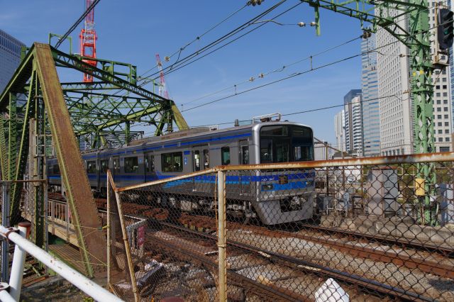 なかなか開かない踏切に沢山の電車が来ます。北総線の車両、京急以外も乗り入れ先から種類も多彩。